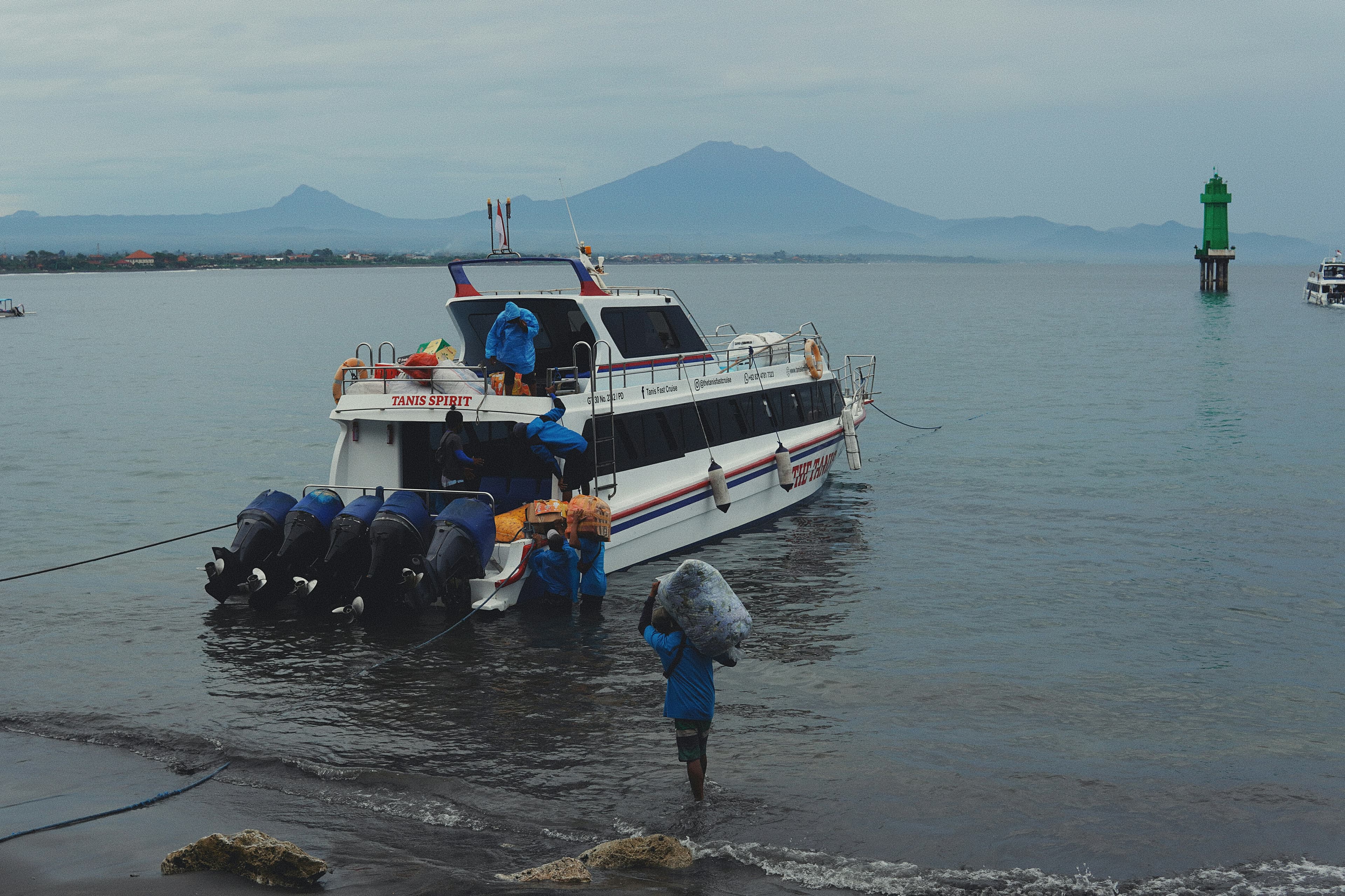 Fast boat at Sanur beach with a porter wading out with luggage